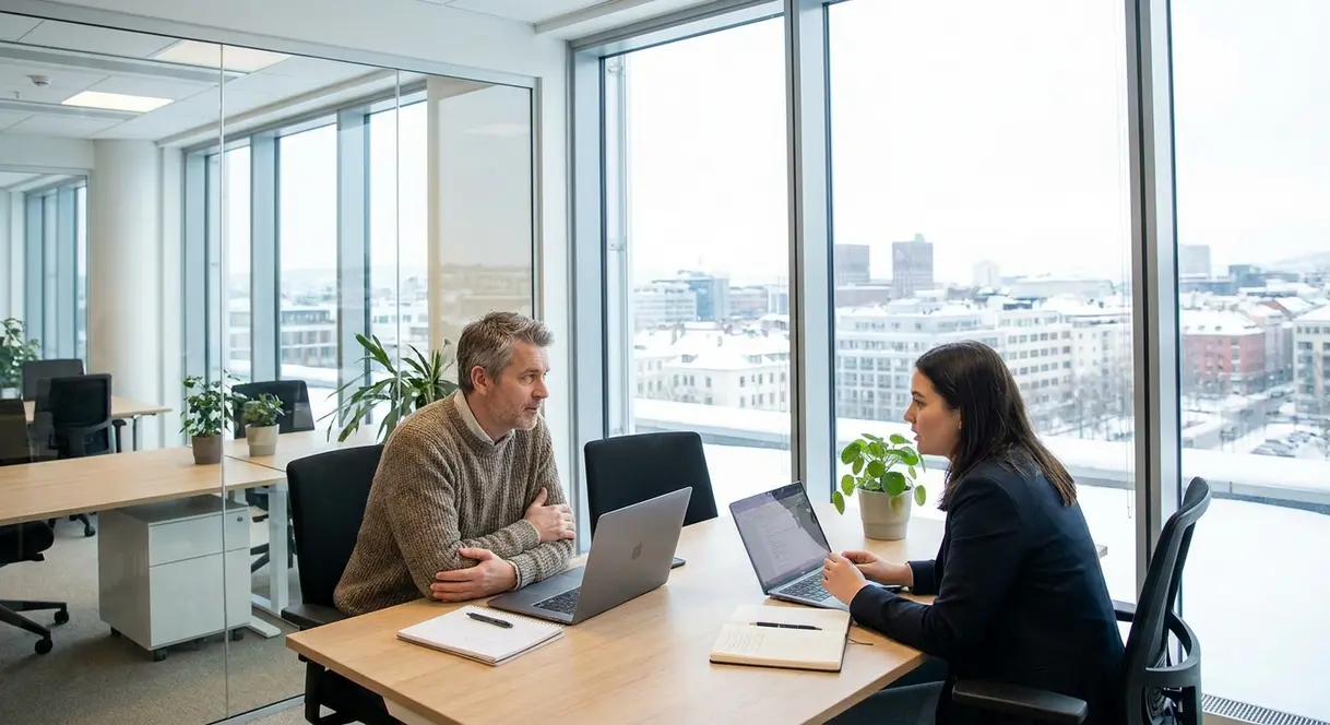 En norsk leder i en moderne kontorsetting som har en seriøs samtale med en ansatt, med fokus på profesjonell veiledning og støtte.